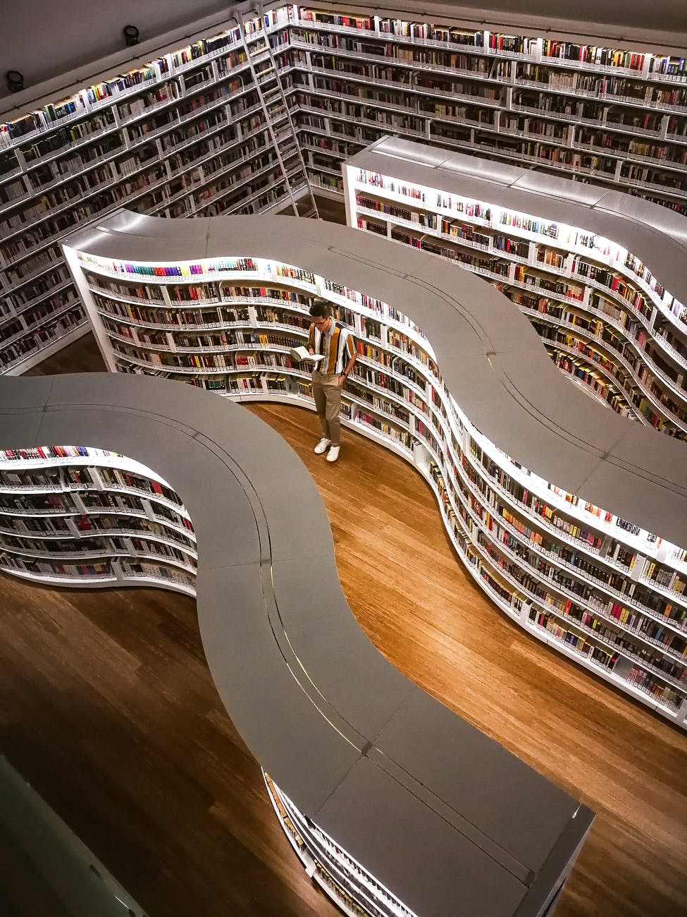 man standing inside library while reading book